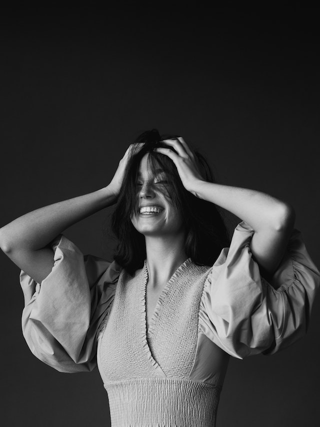 Photo by Maria Orlova: https://www.pexels.com/photo/happy-young-woman-smiling-and-touching-head-with-both-hands-4906284/, happy 