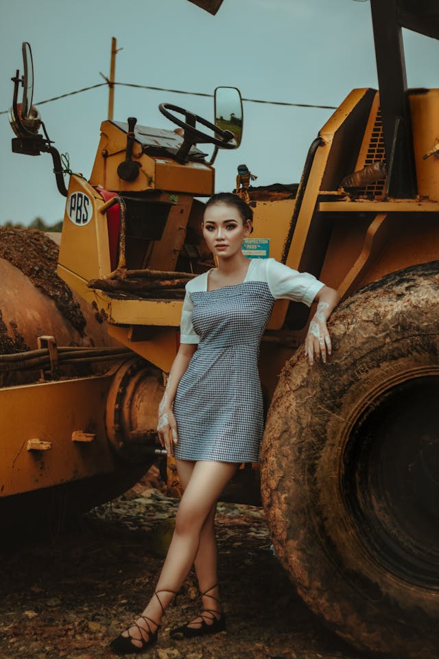 Small girl in a black and white dress leaning on excavator 